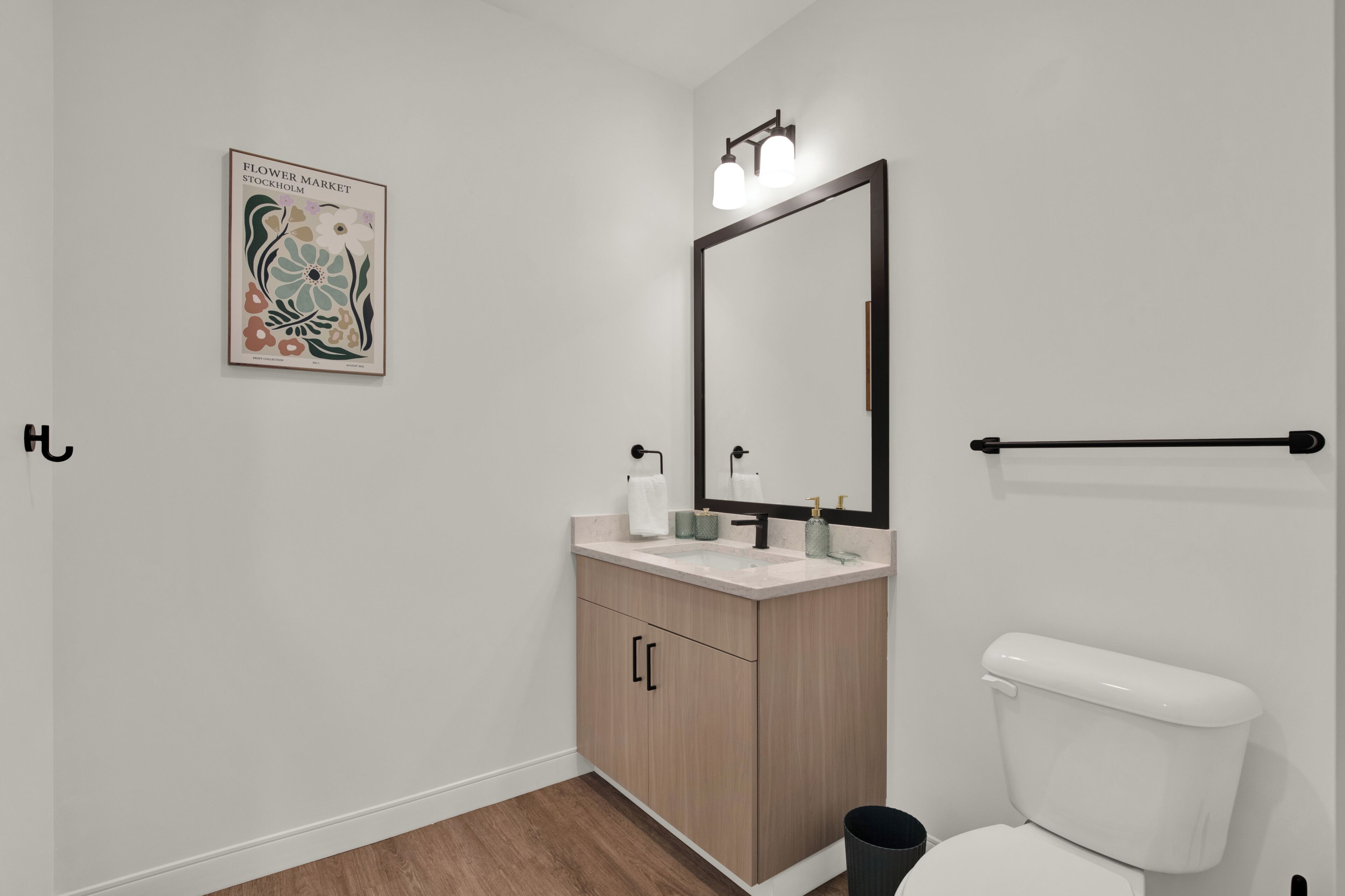 Une salle de bain moderne équipée de toilettes, d’un lavabo, d’un miroir et d’un tableau encadré accroché au mur.