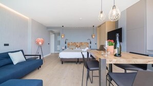 Ein modernes Hotelzimmer mit einem Bett, einem Schreibtisch mit Stühlen, einem Fernseher und einem blauen Sofa.