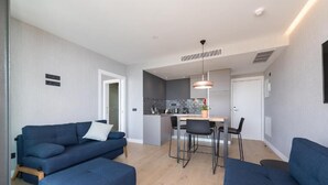 Ein moderner Wohnraum mit Sofa, Hocker, Essbereich und Küche.