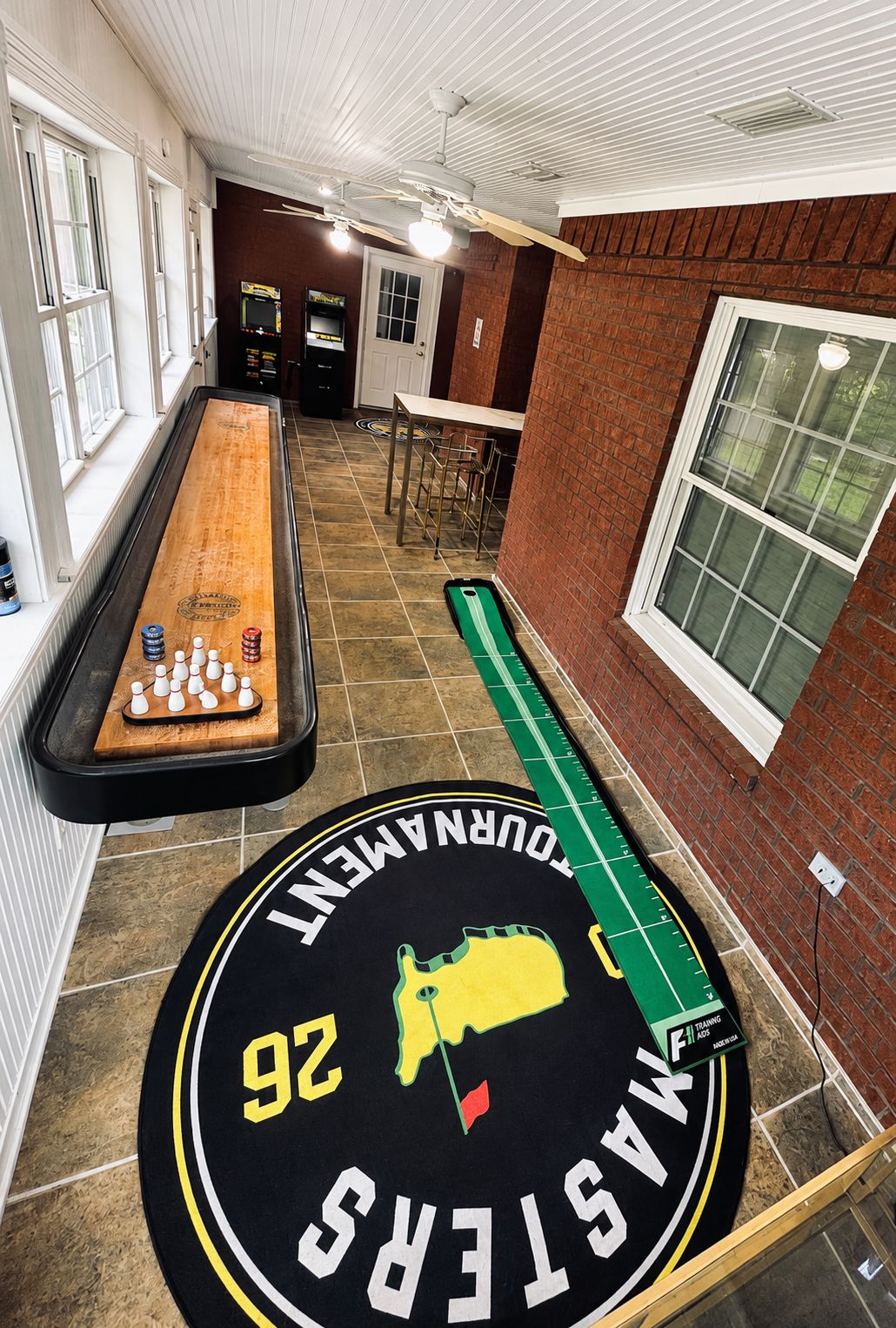 Une table de billard avec une boule blanche et des palets, une table de jeu de palet avec une cible, et un jeu de fléchettes avec le numéro 92.