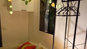 A bedroom with a bed, colorful pillows, a hanging light fixture, and a wall-mounted TV. - Cozy room 15 minutes from Paris-Orly with a bathroom and private terrace (Choisy-le-Roi)
