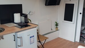 A compact kitchen with a microwave, refrigerator, and a flat-screen TV mounted on the wall. - Cozy room 15 minutes from Paris-Orly with a bathroom and private terrace (Choisy-le-Roi)