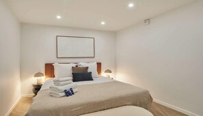 Ein Hotelzimmer mit einem Bett, zwei Nachttischen, einem Wandbild und einer Deckenleuchte.