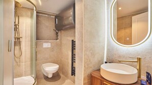 A bathroom with a glass-enclosed shower, a toilet, a vanity with a sink, and a mirror. - COMBINING COMFORT, TRANQUILITY & A PRIME LOCATION MONTMARTRE (Paris)