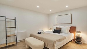A bedroom with a bed, a bedside table, a lamp, a bench, and a ladder against the wall. - COMBINING COMFORT, TRANQUILITY & A PRIME LOCATION MONTMARTRE (Paris)