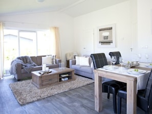 A modern living room with a sofa, coffee table, dining table, and chairs. - Carre Nouveau 4 (Velsen-Zuid)