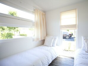 A room with two beds, a window with curtains, and a view of a parking area. - Carre Nouveau 4 (Velsen-Zuid)