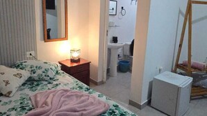 Un dormitorio con cama, mesita de noche, lámpara y aire acondicionado.