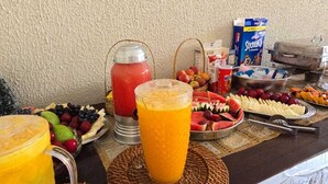 Un bufé de desayuno con diversas frutas, zumos y cajas de cereales.