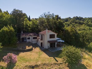 Une maison à deux étages avec un patio et un petit jardin.