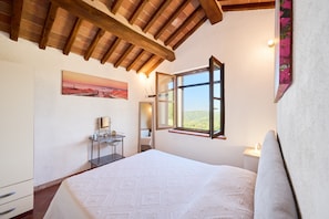 Ein Schlafzimmer mit einem Bett, einem Nachttisch, einem Spiegel, einem Fenster und einem Bild an der Wand.