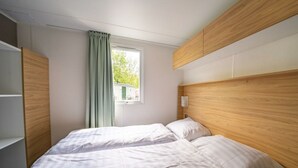 A bedroom with a bed, a window with curtains, and built-in wooden headboards. - Holiday Home in Amstelveen With Terrace (Amstelveen)