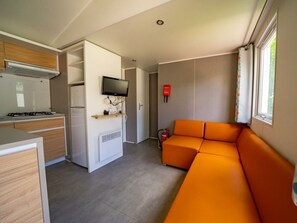 Een compacte keuken met een kookplaat, magnetron en een flatscreen televisie aan de wand.
