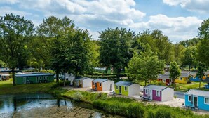 A row of colorful mobile homes by a calm river, surrounded by lush greenery. - Holiday Home in Amstelveen With Terrace (Amstelveen)