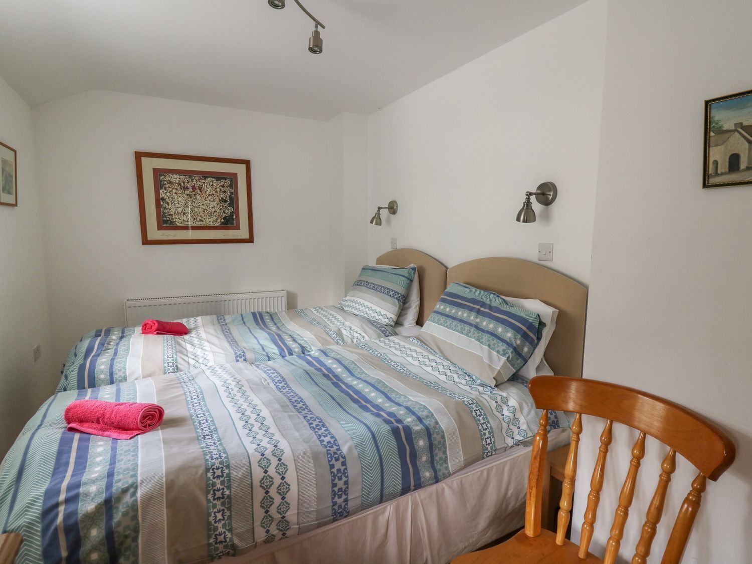 A bedroom with a bed, a chair, a radiator, and a framed picture on the wall.