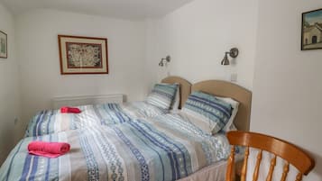 A bedroom with a bed, a chair, a radiator, and a framed picture on the wall.