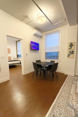 Ein modernes Wohnzimmer mit Esstisch, Flachbildfernseher und großem Fenster.
