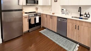 A modern kitchen with stainless steel appliances, wooden cabinets, and a white countertop.
