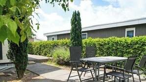 An outdoor patio with a table and chairs, a hedge, and a building in the background. - Holiday Home in Dordrecht With Terrace (Dordrecht)
