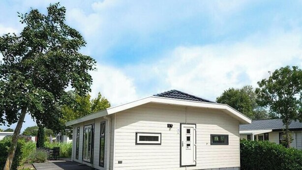 A single-story mobile home with a flat roof, a front door, and a small window. - Holiday Home in Dordrecht With Terrace (Dordrecht)