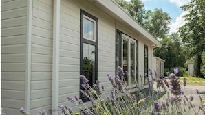 A single-story building with a light-colored siding exterior, large windows, and a garden with lavender plants. - Holiday Home in Dordrecht With Terrace (Dordrecht)