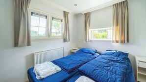 A room with two beds, a radiator, a window, and curtains. - Holiday Home in Dordrecht With Terrace (Dordrecht)