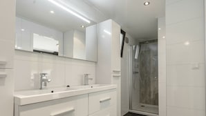 Un baño moderno con lavamanos doble, un espejo grande y zona de ducha.