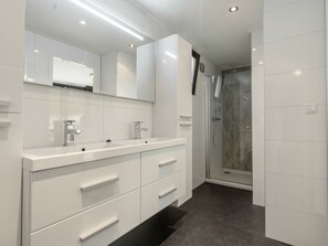 A modern bathroom with a double sink, a large mirror, and a shower area. - Cube Exclusive 4 (Breskens)