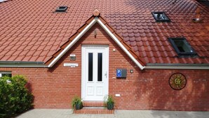 Ein Gebäude mit roten Ziegeln, einer weißen Tür, einem Parkschild und einem kleinen Fenster.