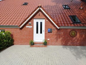 A red-tiled building with a white door, a parking sign, and a small window.