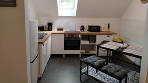 Eine kleine Küche mit Fenster, einer Mikrowelle, einer Kaffeemaschine und einer Waschmaschine.