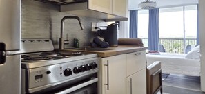 Une cuisine de taille réduite, équipée d’une cuisinière, d’un four et d’un petit plan de travail.