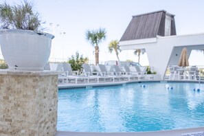 Ein Schwimmbecken mit Liegestühlen, einer Topfpflanze und einem modernen Gebäude im Hintergrund.