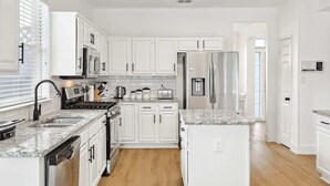 Eine moderne Küche mit weißen Schränken, Granit-Arbeitsplatten, Edelstahlgeräten und einem Holzboden.
