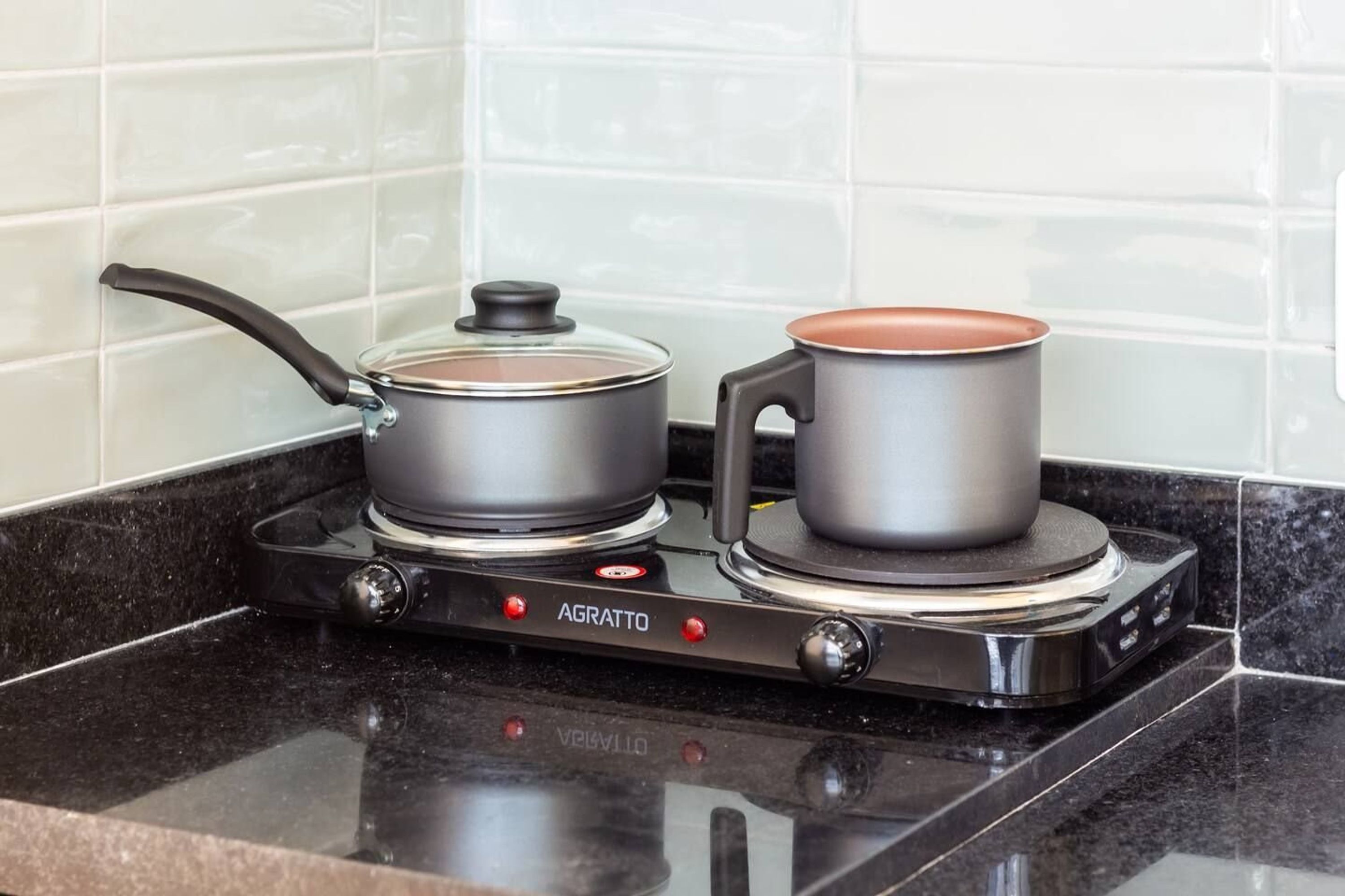 A kitchen with a stove, pots, and a kettle.