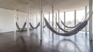 Quarto espaçoso com design moderno, com uma janela grande e uma rede pendurada entre colunas.