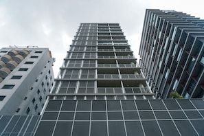 Un immeuble de grande hauteur doté d’une façade à motifs géométriques, de nombreux balcons et d’une conception architecturale moderne.