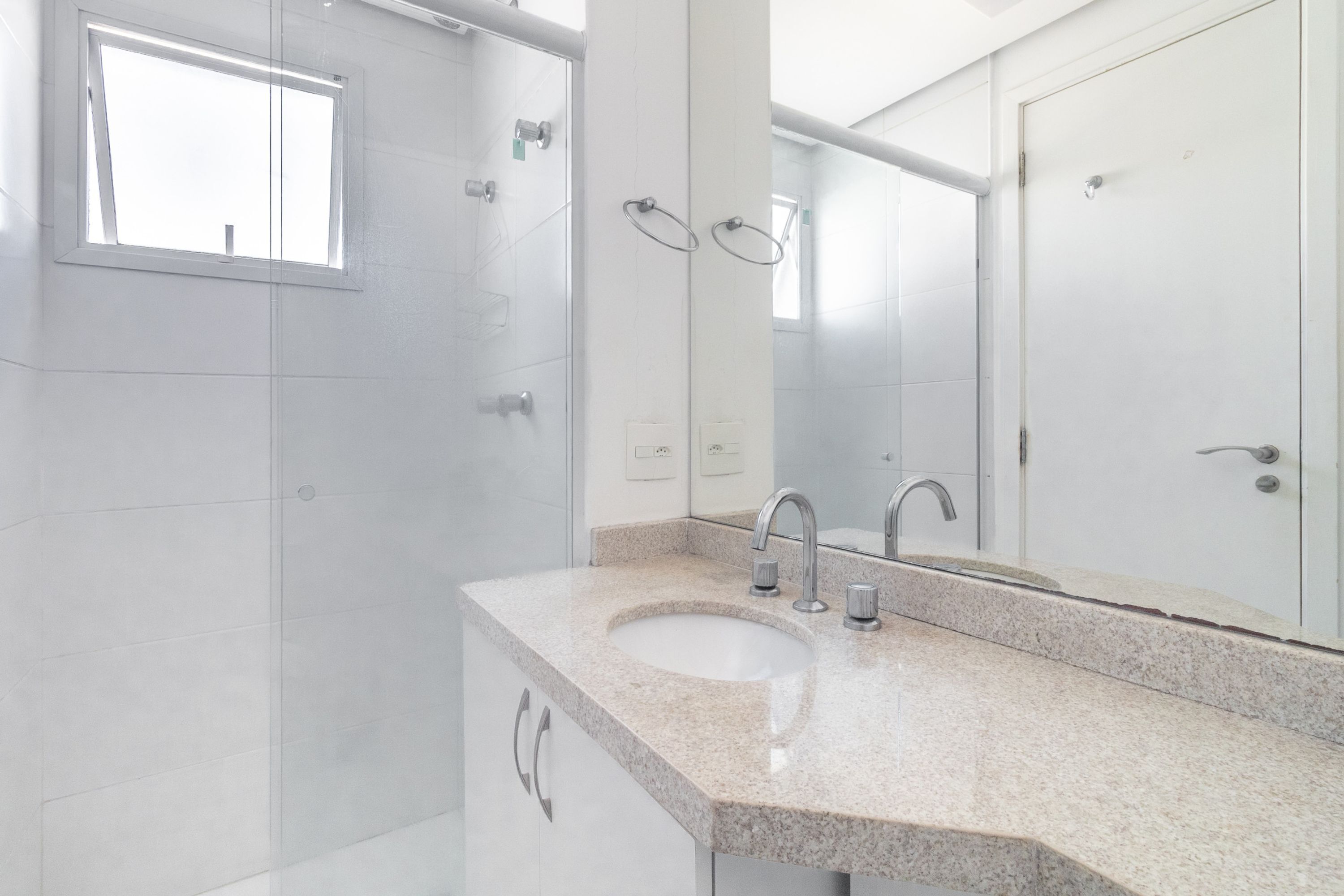 Un baño moderno con lavamanos de granito, espejo y zona de ducha.