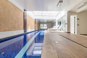 A swimming pool with tiled walls and a wooden floor, a glass door, and a view of the outside. - Hype133 1q 2p in S o Paulo (São Paulo)