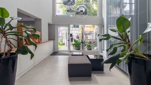 Ein modernes Interieur mit einer Sitzecke, großen Fenstern und Topfpflanzen.