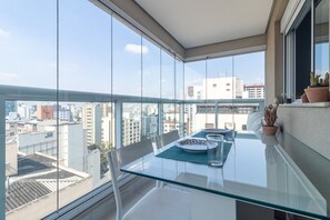 A balcony with a glass table, chairs, and potted plants. - Hype133 1q 2p in S o Paulo (São Paulo)