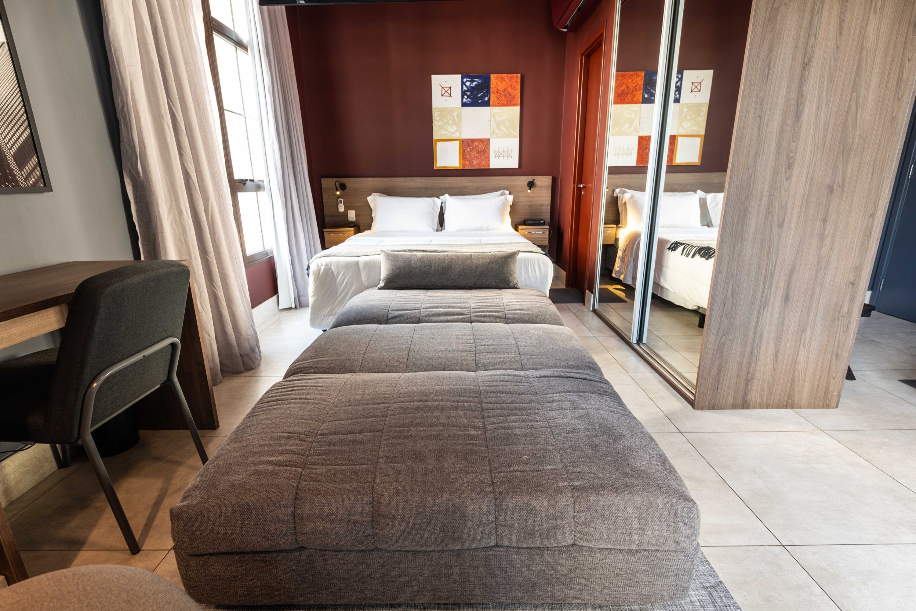 A hotel room with a bed, a desk, and a chair.