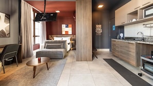A modern living room with a sofa, coffee table, and a TV. There is a kitchen area with cabinets and a microwave. - Jp047 Jacques Pilon Residence 3 Pessoas (São Paulo)