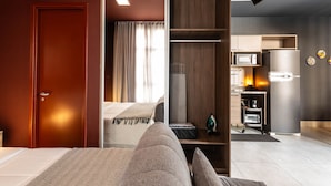 A modern hotel room with a bed, a wardrobe, a kitchenette, and a television. - Jp047 Jacques Pilon Residence 3 Pessoas (São Paulo)