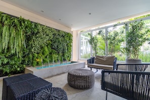 Un espace intérieur moderne agrémenté d’un jardin vertical, d’un coin salon et de grandes fenêtres.