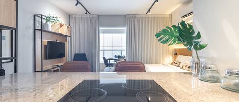 Una cocina moderna con una placa de inducción integrada, un televisor de pantalla plana y un área de descanso con vistas a la ciudad.