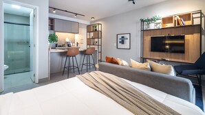 A modern living room with a sofa, TV, and a kitchen area with stools. - Landing 508 in S o Paulo (São Paulo)