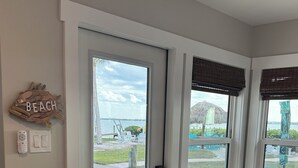 Una habitación con vista a la playa, una puerta, un banco y una mesa.