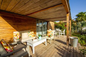 Eine Holzterrasse mit einer Couch, Stühlen und einem Tisch.