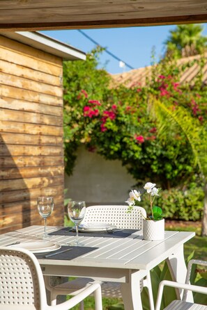 Eine Terrasse im Freien mit einem Tisch für zwei Personen, komplett mit Weingläsern und einem kleinen Blumentopf.